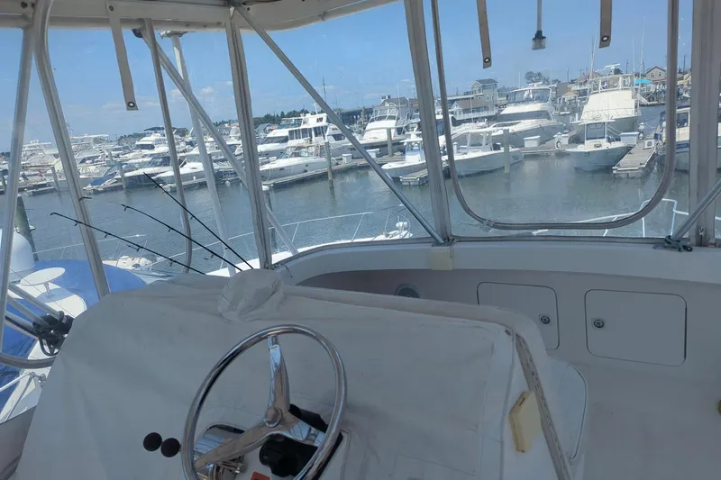  Yacht Photos Pics 2005 Luhrs 36 Convertible yacht interior with marina view, featuring steering wheel and fishing rods.