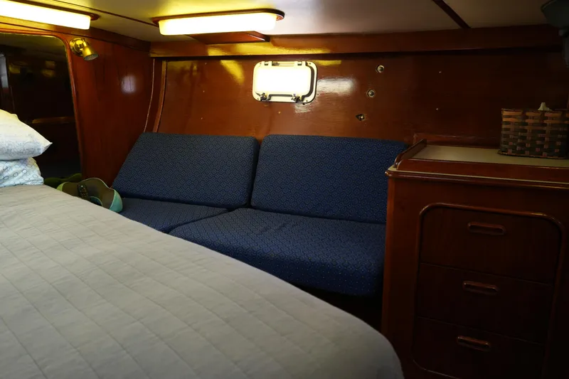 Peggy Lee Yacht Photos Pics Interior of 1984 Irwin 52 Cutter Ketch with blue sofa and wooden cabinetry.