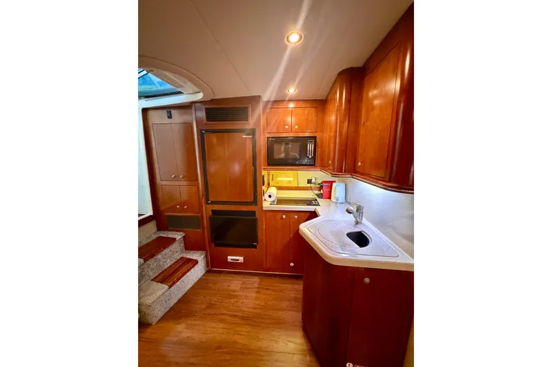  Yacht Photos Pics 2007 Cruisers Yachts 370 Express interior kitchen with wood cabinetry and modern appliances.
