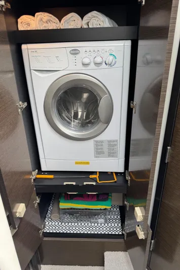  Yacht Photos Pics Compact laundry area with washer in 2017 Cruisers Yachts 45 Cantius, towels neatly stored above.