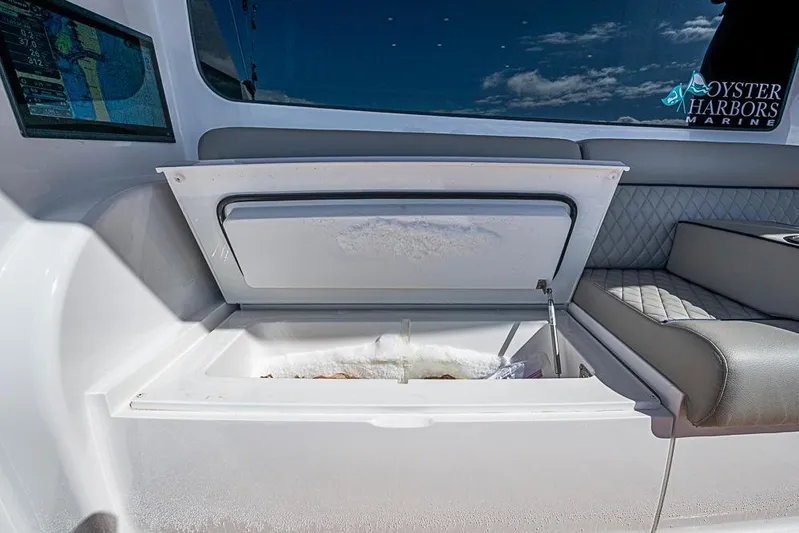 Big Stink Yacht Photos Pics Open storage compartment on 2026 Viking 54 Convertible yacht, featuring cushioned seating and navigation display.