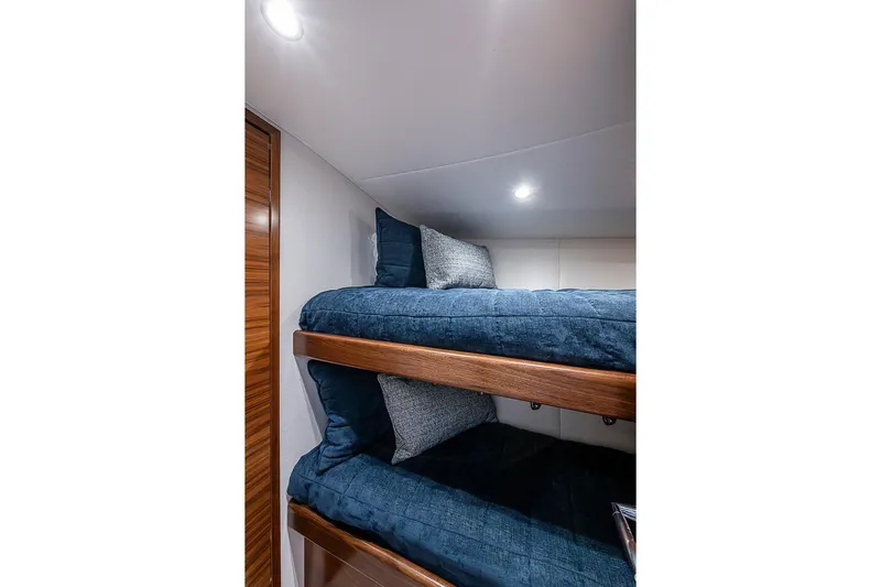 Big Stink Yacht Photos Pics Bunk beds in 2026 Viking 54 Convertible yacht cabin with blue bedding and wooden accents.