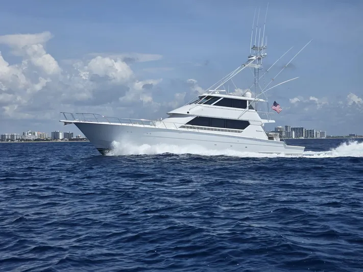 Triple Net II Yacht Photos Pics 1994 Hatteras 82 Convertible yacht cruising on open sea with city skyline in background.