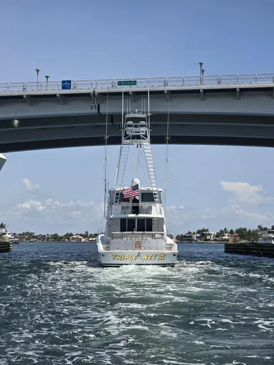 Triple Net II Yacht Photos Pics Hatteras 82 Convertible yacht from 1994 passing under a bridge on a sunny day.