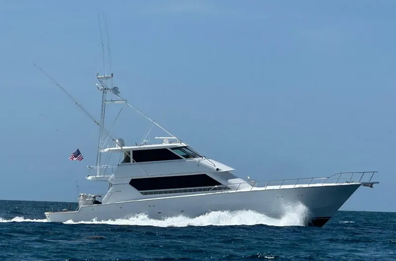 Triple Net II Yacht Photos Pics 1994 Hatteras 82 Convertible yacht cruising on open sea with American flag.