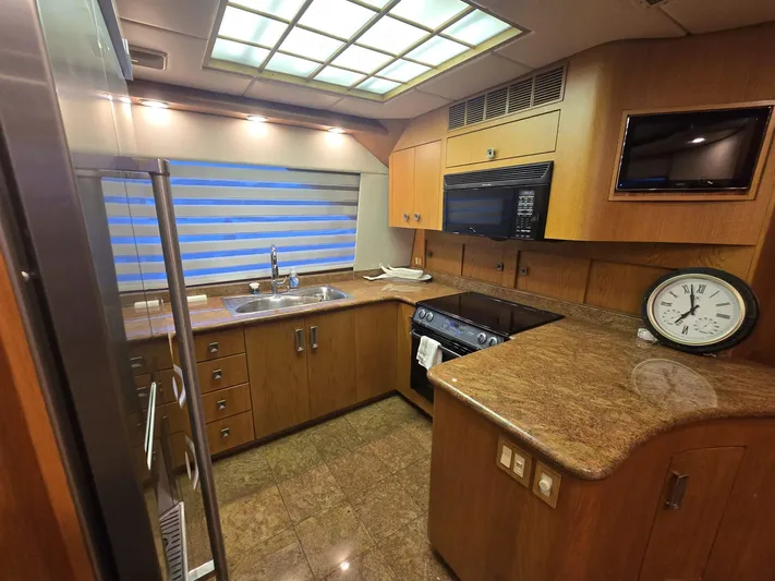 Triple Net II Yacht Photos Pics Kitchen interior of 1994 Hatteras 82 Convertible yacht with modern appliances and wood cabinetry.