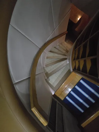 Triple Net II Yacht Photos Pics Curved staircase inside 1994 Hatteras 82 Convertible yacht, featuring wooden handrails and modern design.