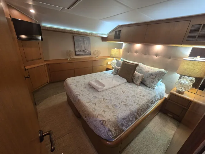 Triple Net II Yacht Photos Pics Luxurious bedroom interior of 1994 Hatteras 82 Convertible yacht with elegant bedding and ambient lighting.