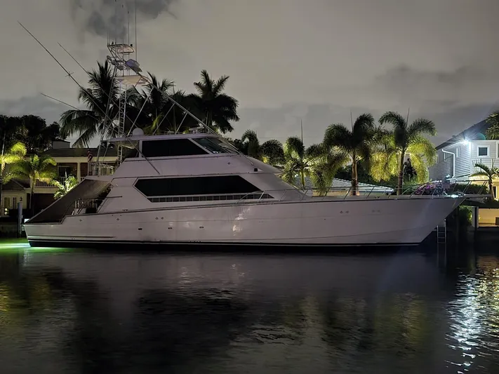 Triple Net II Yacht Photos Pics 1994 Hatteras 82 Convertible yacht docked at night, surrounded by palm trees.