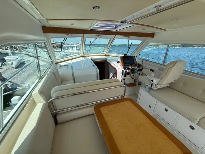 Wahoowa Yacht Photos Pics 2019 Back Cove Downeast boat interior with helm, seating, and table, docked by the water.