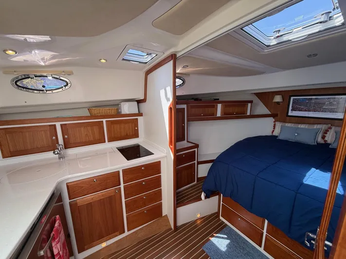 Wahoowa Yacht Photos Pics 2019 Back Cove Downeast interior with wood cabinetry, compact kitchen, and cozy sleeping area.
