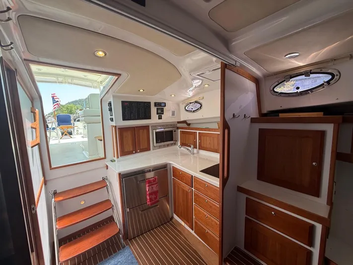 Wahoowa Yacht Photos Pics 2019 Back Cove Downeast yacht interior with wooden cabinetry, kitchenette, and outdoor view.