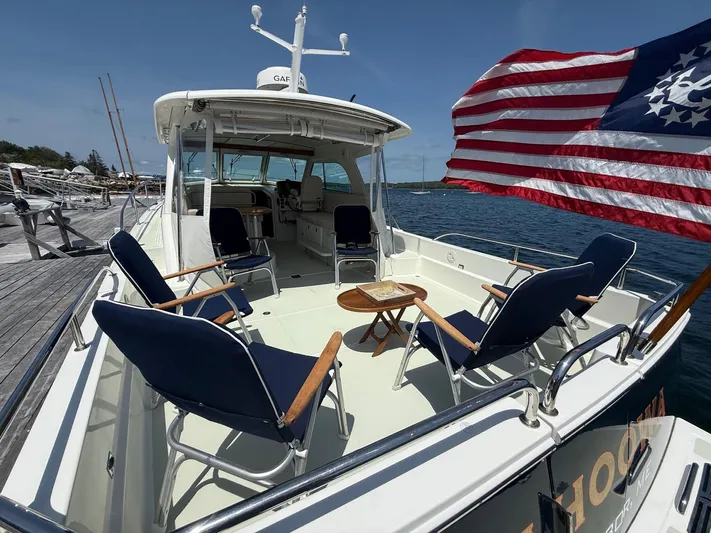 Wahoowa Yacht Photos Pics 2019 Back Cove Downeast boat with seating, American flag, docked by the water.