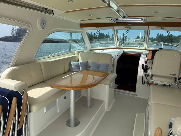 Wahoowa Yacht Photos Pics 2019 Back Cove Downeast boat interior with beige seating, wooden table, and scenic water view.