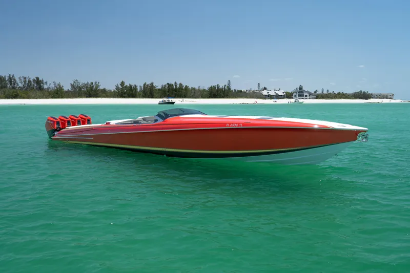 Lady Lisa Yacht Photos Pics 2023 Nor-Tech 55 Flyer boat in vibrant red on turquoise water near a sandy beach.