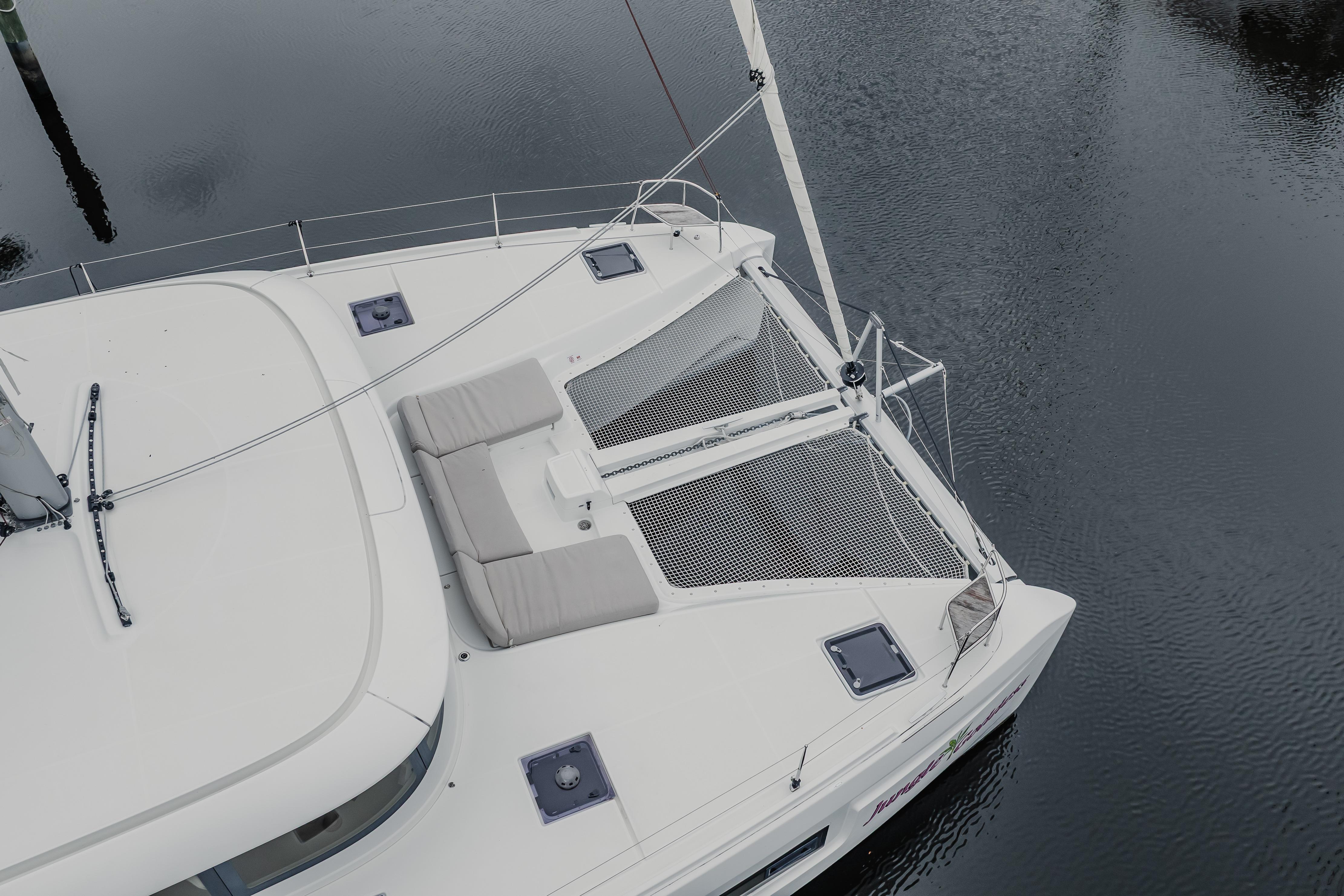 Aerial view of 2022 Lagoon 46 catamaran with netted deck and cushioned seating.