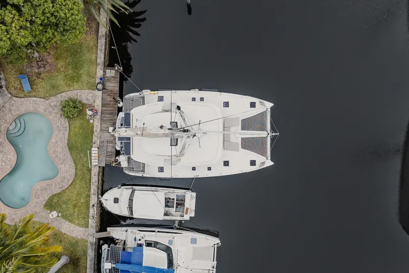 Yacht Photos Pics Aerial view of a 2022 Lagoon 46 catamaran docked near a pool and greenery.