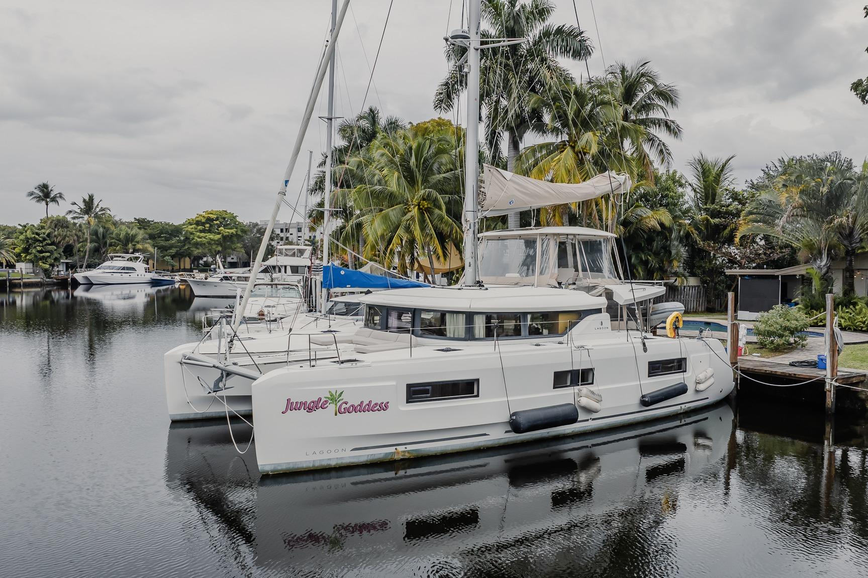 2022 Lagoon 46 catamaran "Jungle Goddess" docked by palm trees in a serene marina.