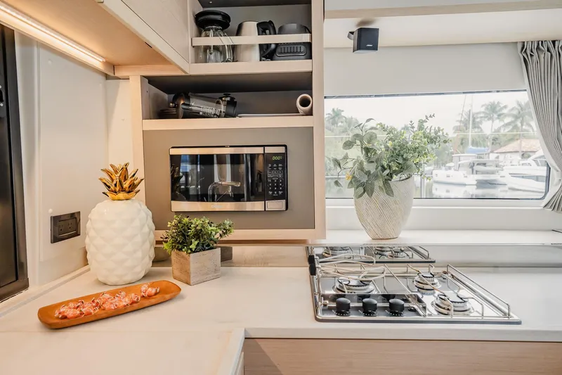  Yacht Photos Pics Modern kitchen interior of 2022 Lagoon 46 yacht with microwave and stove.