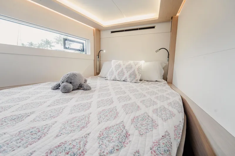  Yacht Photos Pics Luxurious bedroom interior of 2022 Lagoon 46 yacht with plush bedding and soft lighting.