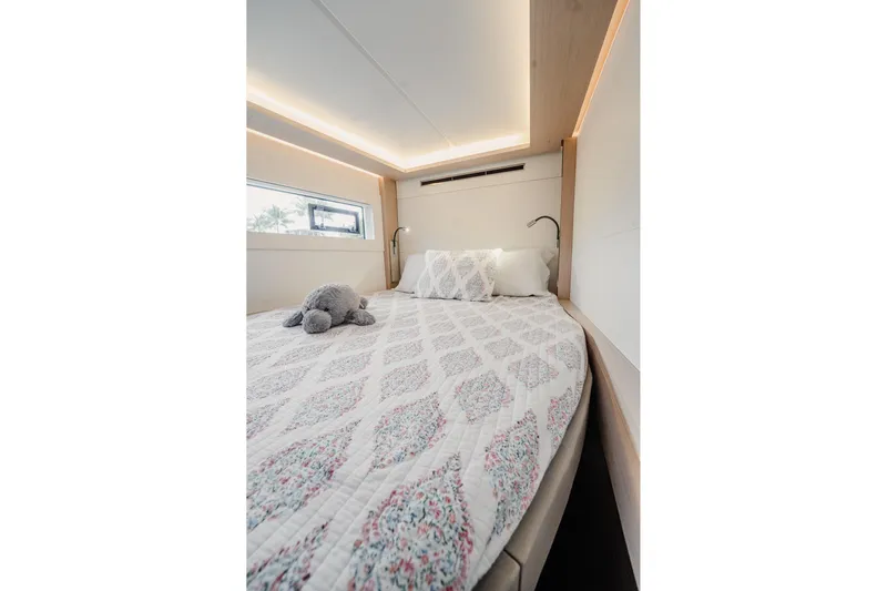  Yacht Photos Pics Luxurious bedroom interior of 2022 Lagoon 46 yacht with elegant bedding and soft lighting.