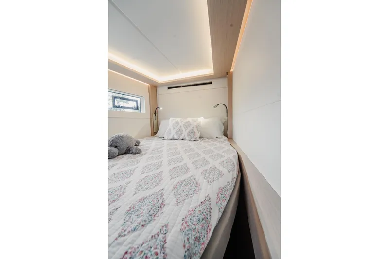  Yacht Photos Pics Luxurious bedroom interior of 2022 Lagoon 46 yacht with elegant bedding and soft lighting.