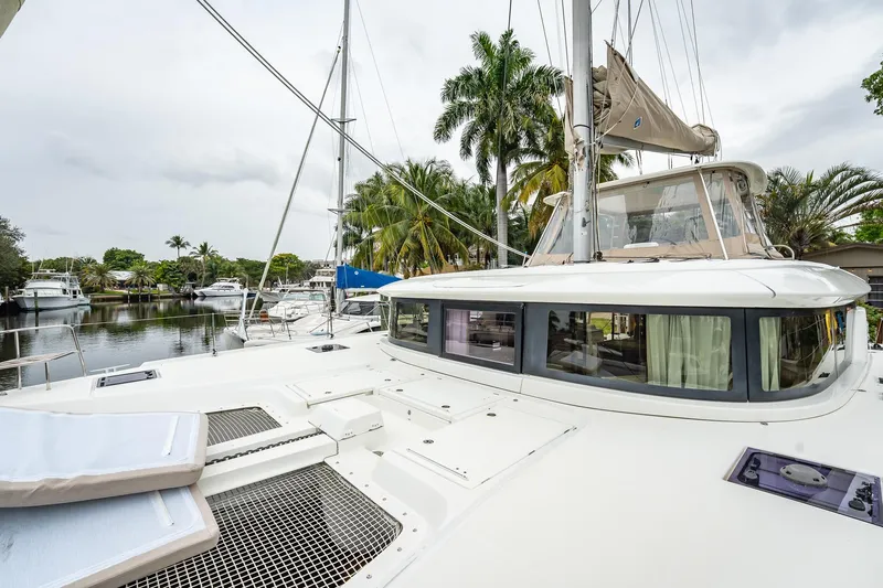  Yacht Photos Pics 2022 Lagoon 46 catamaran docked near palm trees, showcasing sleek design and spacious deck.