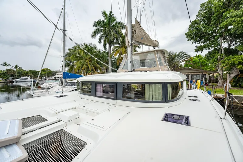  Yacht Photos Pics 2022 Lagoon 46 catamaran docked, surrounded by palm trees and other boats.