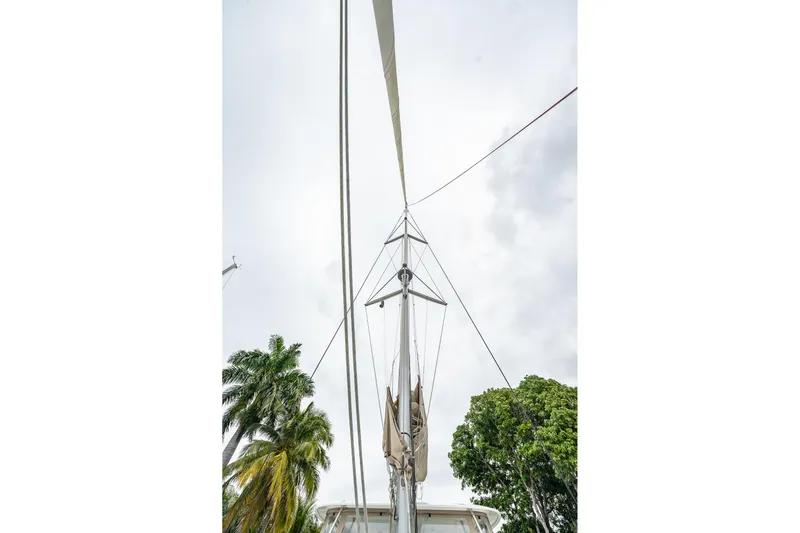  Yacht Photos Pics Mast of 2022 Lagoon 46 sailboat against cloudy sky and palm trees.