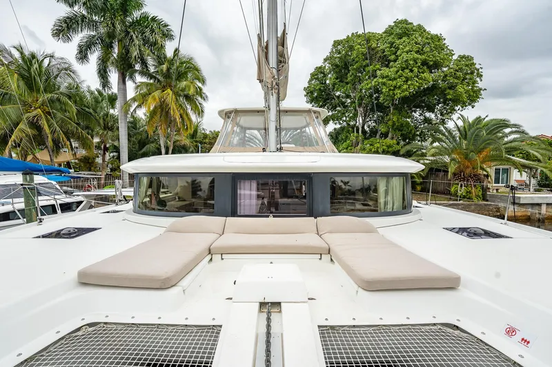  Yacht Photos Pics 2022 Lagoon 46 catamaran with sunbathing area, surrounded by tropical palm trees.