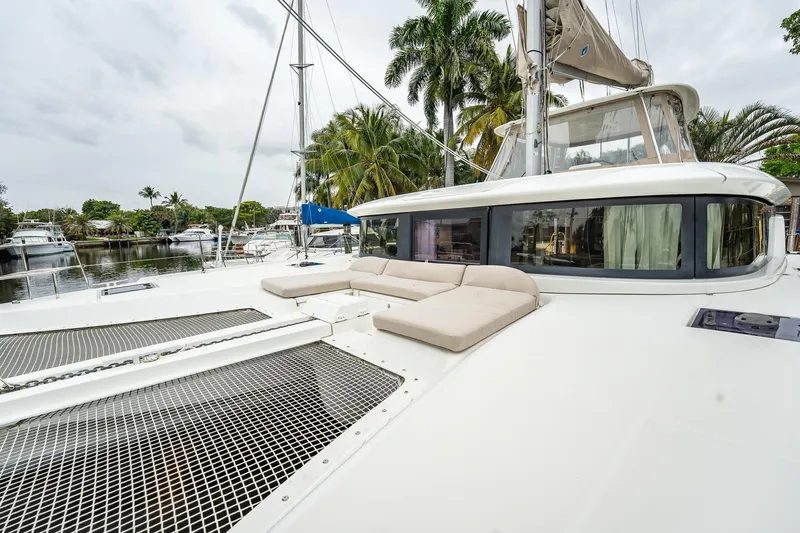  Yacht Photos Pics 2022 Lagoon 46 catamaran with spacious deck and lounging area, docked near palm trees.