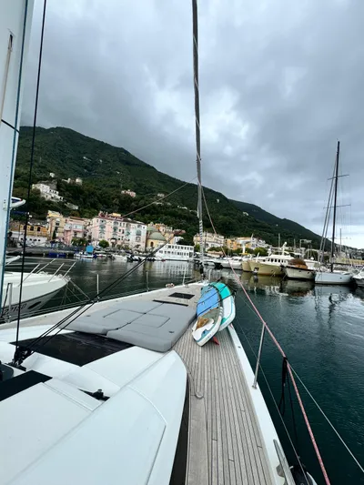 Blue Art Yacht Photos Pics 2023 Jeanneau 65 yacht docked in scenic harbor with cloudy skies.