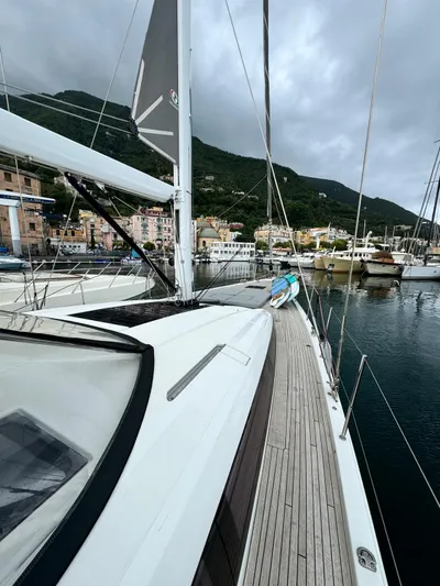 Blue Art Yacht Photos Pics 2023 Jeanneau 65 yacht docked in scenic marina with mountainous backdrop.