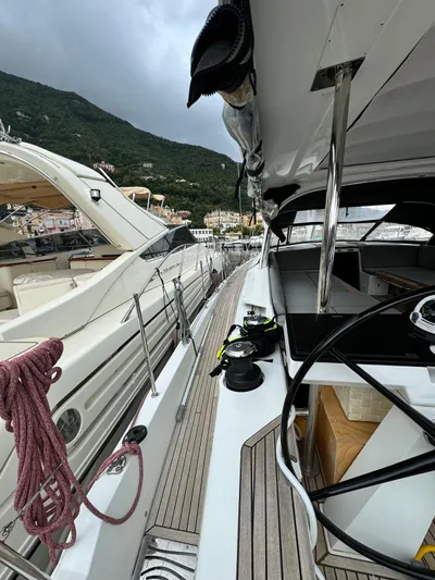 Blue Art Yacht Photos Pics 2023 Jeanneau 65 yacht deck with steering wheel, docked in scenic marina.