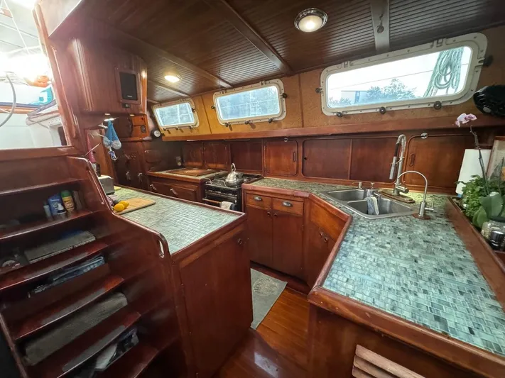 Pacific High Yacht Photos Pics Vintage 1983 Custom 62 yacht kitchen with wooden cabinetry and tiled countertops.