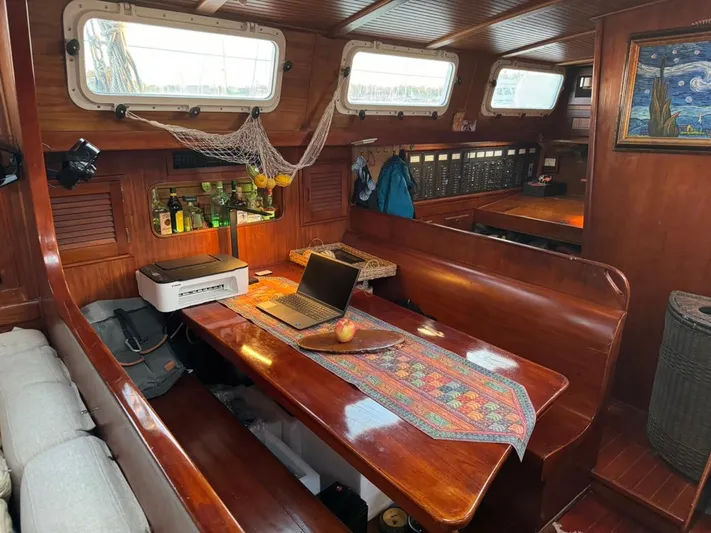Pacific High Yacht Photos Pics Cozy 1983 Custom 62 yacht interior with wooden dining area, laptop, and nautical decor.