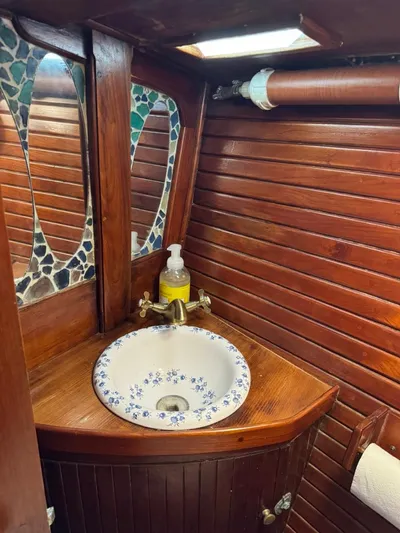 Pacific High Yacht Photos Pics Wood-paneled bathroom with floral sink, mosaic mirrors, and vintage nautical design, Custom 62, 1983.