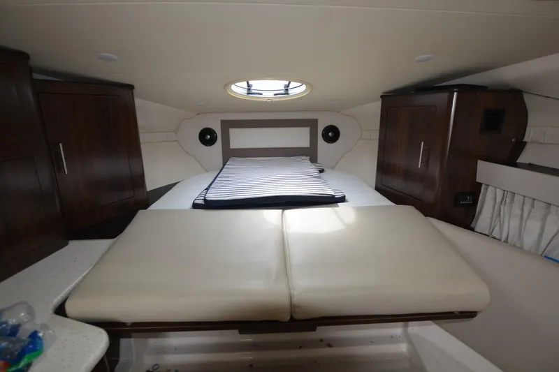 Mountaineer Mayhem Yacht Photos Pics 2018 Regal 33XO cabin interior with bed, wooden cabinets, and circular skylight.