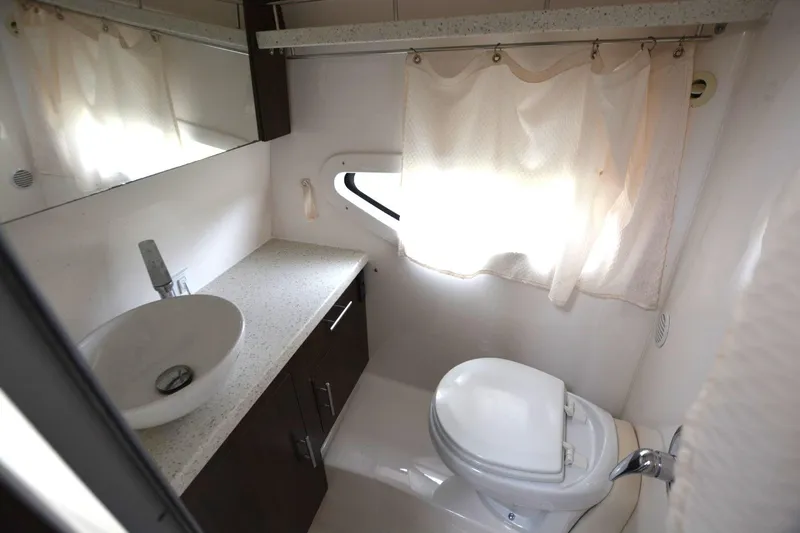 Mountaineer Mayhem Yacht Photos Pics 2018 Regal 33XO boat bathroom with sink, toilet, and window curtain.