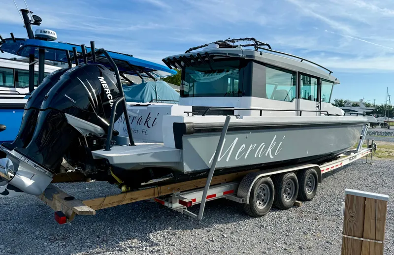 Meraki Yacht Photos Pics 2019 Axopar AX37XC boat on trailer with Mercury engine, labeled "Meraki," parked on gravel.