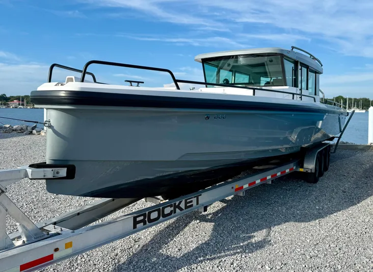 Meraki Yacht Photos Pics 2019 Axopar AX37XC boat on trailer by the water, clear sky background.