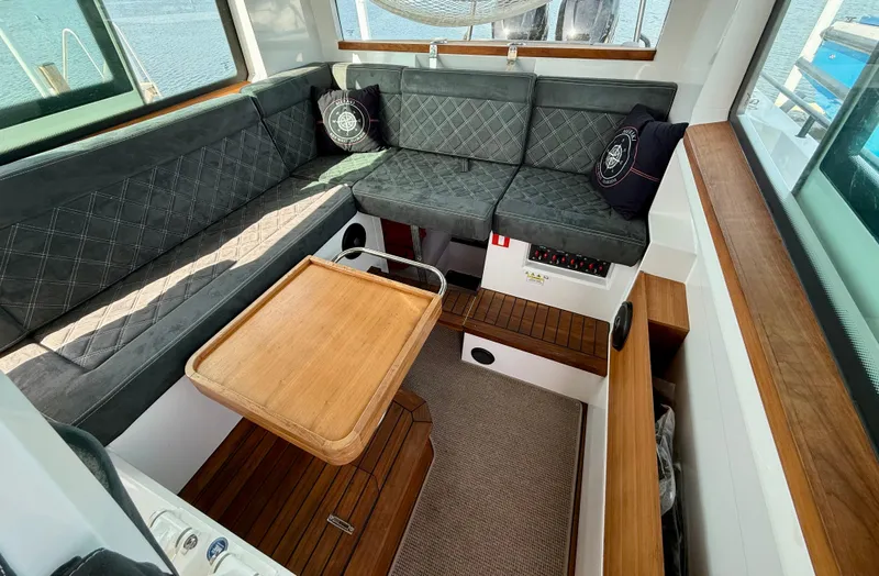 Meraki Yacht Photos Pics Interior of 2019 Axopar AX37XC boat with cushioned seating and wooden table.