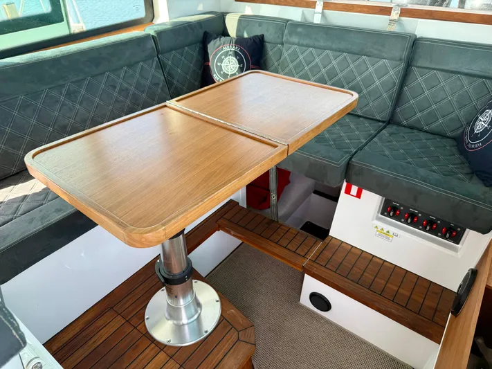 Meraki Yacht Photos Pics Interior of 2019 Axopar AX37XC boat with wooden table and cushioned seating.