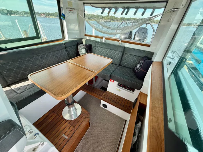 Meraki Yacht Photos Pics 2019 Axopar AX37XC interior with wooden table, cushioned seating, and scenic water view.