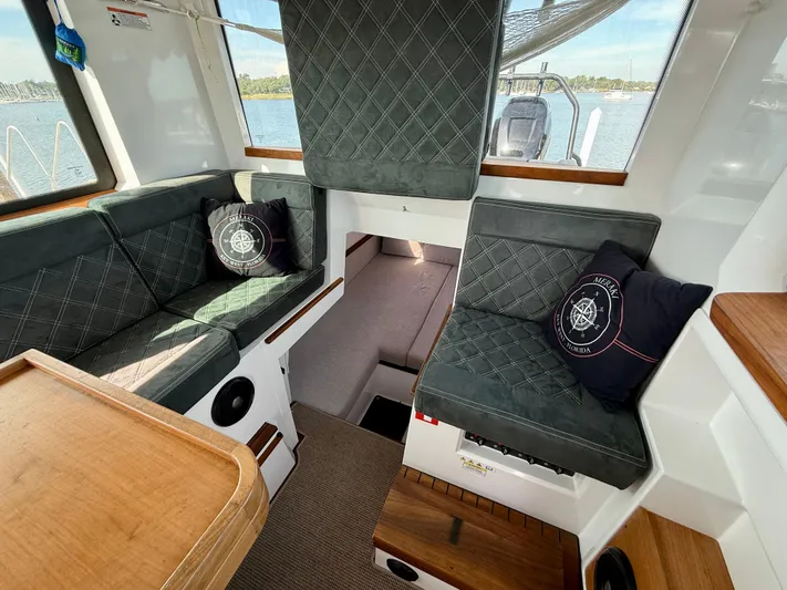 Meraki Yacht Photos Pics 2019 Axopar AX37XC interior with cushioned seating and nautical-themed pillows.