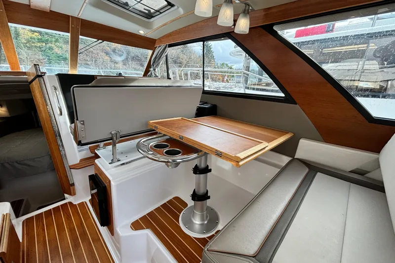  Yacht Photos Pics Interior of 2023 Cutwater C-32 Coupe with wooden table and seating area.