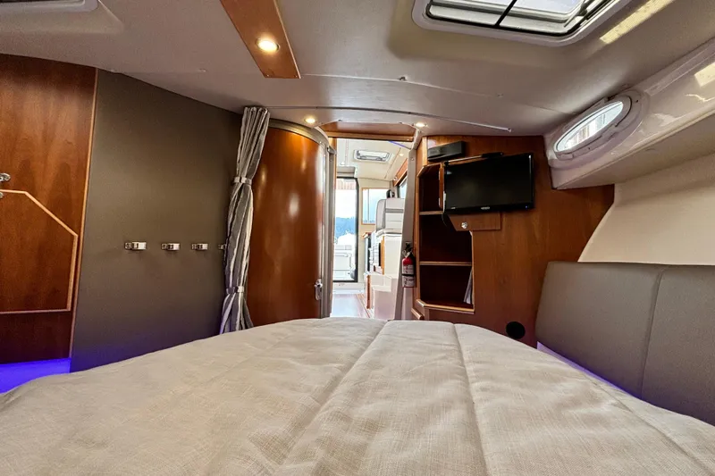  Yacht Photos Pics 2023 Cutwater C-32 Coupe interior cabin with bed, TV, and wooden accents.