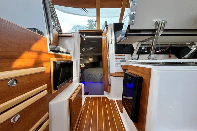  Yacht Photos Pics 2023 Cutwater C-32 Coupe interior with wood accents, modern appliances, and cozy sleeping area.