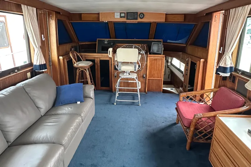 Double Play Yacht Photos Pics Interior of 1980 Hatteras 58 Yachtfish with blue carpet, leather sofa, and wooden helm.