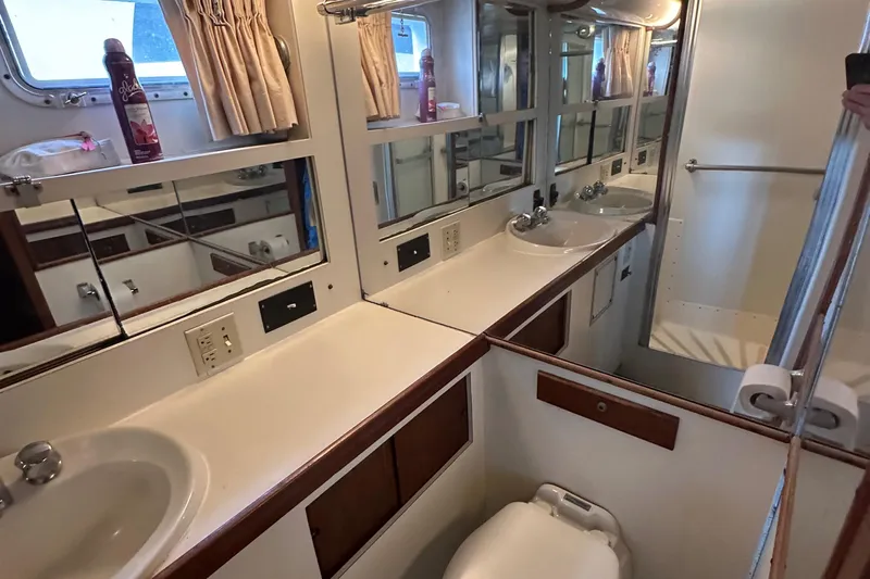 Double Play Yacht Photos Pics 1980 Hatteras 58 Yachtfish bathroom with dual sinks, mirrors, and shower.